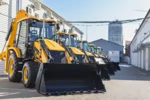 A lineup of yellow industrial excavators in an alley.