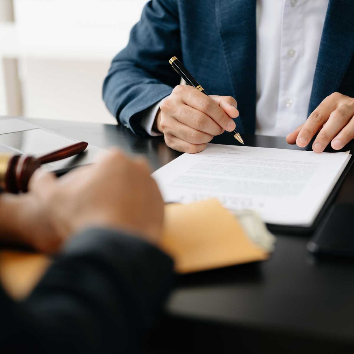 A signatory party signing documents in front of an arbitrator